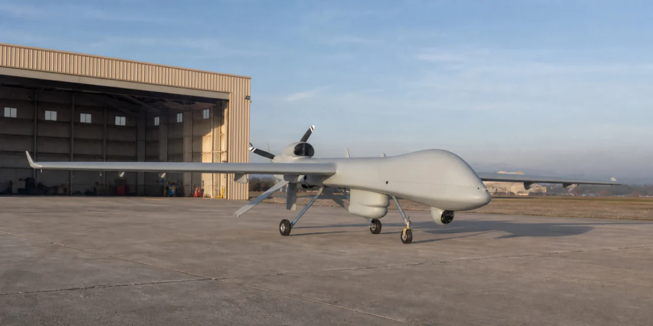 Uncrewed aircraft parked outside an airfield hangar